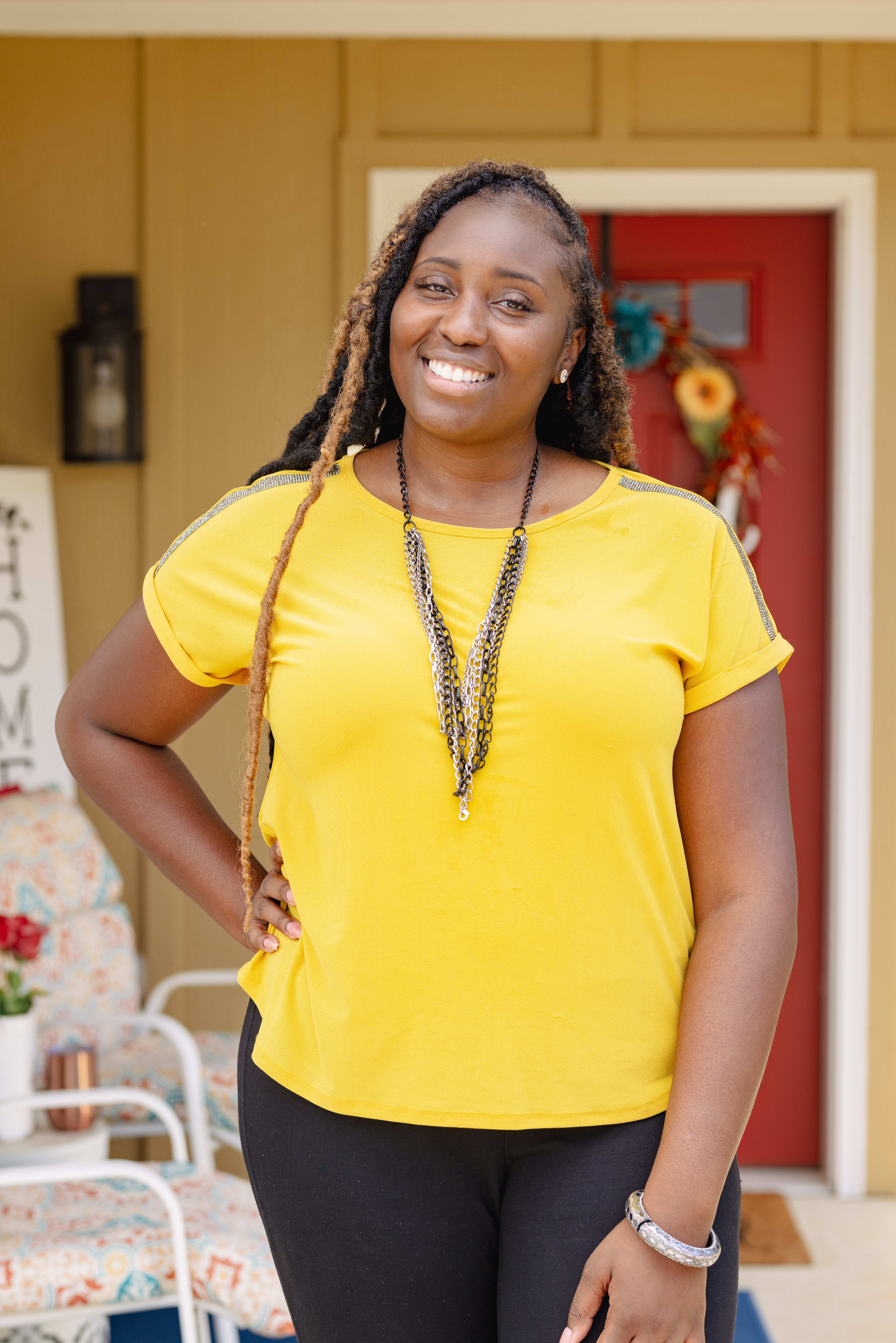 woman in yellow shirt standing in front of her house